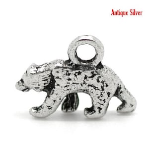 May include: Antique silver bear charm. This small, detailed charm features a bear walking on all fours. The charm has a textured surface and a loop at the top for attaching to a necklace or bracelet. The text "Antique Silver" is visible.