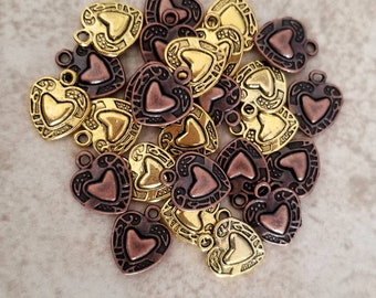 May include: A collection of heart-shaped charms in bronze and gold tones. Each charm features a heart-shaped center and decorative border. The charms have a small loop at the top for attaching to jewelry or other crafts.