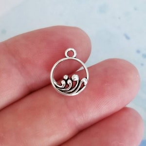 May include: Silver charm with a wave design inside a circle. The charm is perfect for jewelry making or adding a nautical touch to crafts.