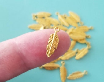 May include: Gold feather charm with a loop at the top. The charm is about 1 inch long and has a detailed design.