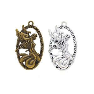 May include: Two oval-shaped metal charms featuring a fairy with wings. One charm is silver and the other is bronze.