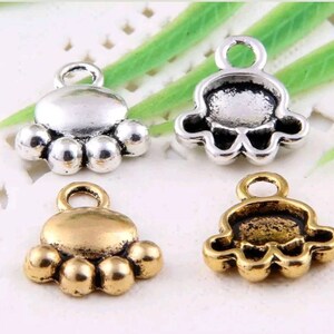 May include: Four silver and gold paw print charms with a loop for attaching to jewelry or other crafts.