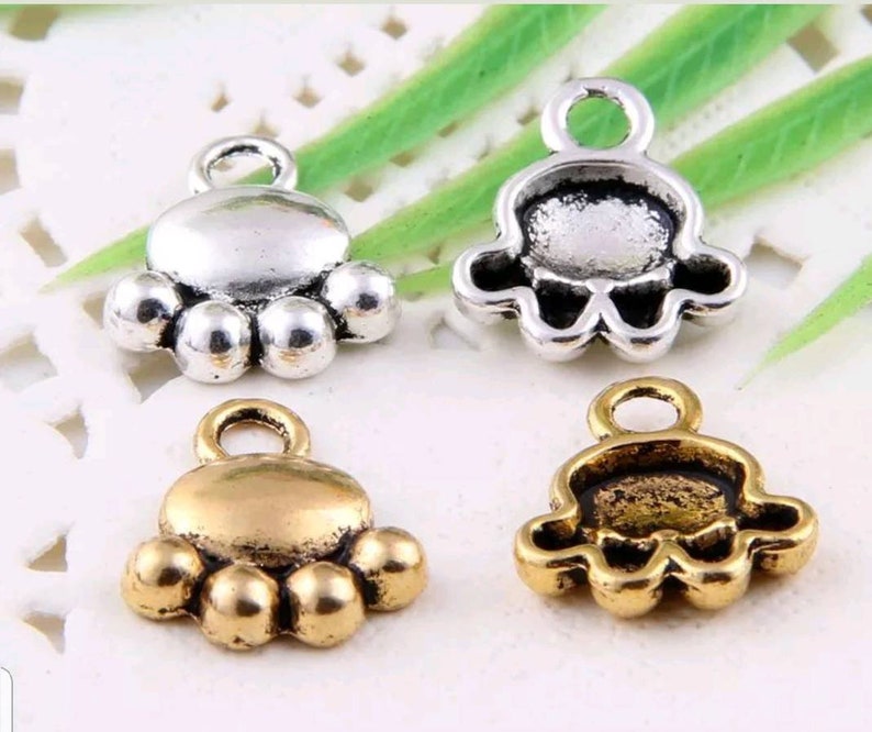 May include: Four silver and gold paw print charms with a loop for attaching to jewelry or other crafts.