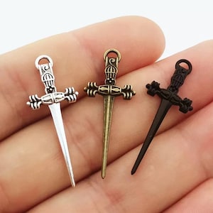 May include: Three silver, bronze, and black sword charms with intricate details. The swords have a pointed tip and a decorative handle.