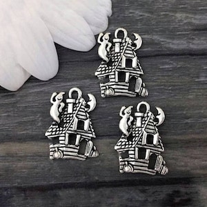 Op de afbeelding: Drie zilveren bedels in de vorm van spookhuizen met geesten en vleermuizen. De bedels zijn gedetailleerd en hebben een vintage uitstraling.