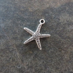 May include: Silver-toned starfish charm with a textured surface. The charm has a loop at the top for attaching to jewelry or other crafts.