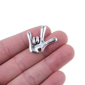 May include: Silver charm in the shape of a hand making the sign for 'I love you' in American Sign Language. The charm has the words 'I LOVE YOU' engraved on it.