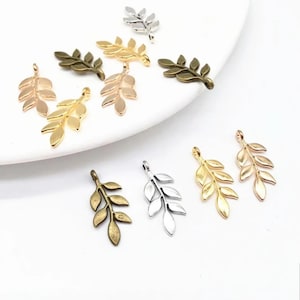 May include: Assortment of gold, silver, and bronze leaf charms. Each charm features a delicate branch with multiple leaves.
