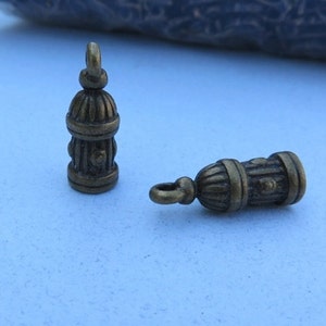 May include: Two antique gold-toned metal charms shaped like fire hydrants. The charms have a detailed design and are perfect for jewelry making or crafting.