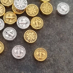 May include: A collection of round, silver and gold metal charms featuring a religious icon. The charms have a raised design and are perfect for jewelry making.