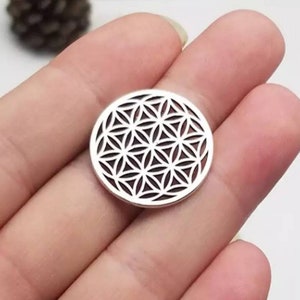 May include: A silver charm with a geometric flower of life design.