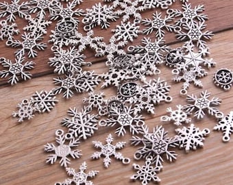May include: A collection of silver snowflake charms, perfect for adding a touch of winter magic to your jewelry making projects.