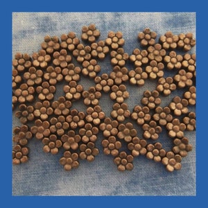 May include: A group of small, copper-colored metal flower charms. Each charm is made up of a cluster of small circles, resembling a flower blossom.