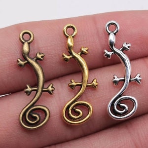 May include: Three metal lizard charms in gold, silver, and bronze finishes. Each charm features a curled tail and detailed lizard features.
