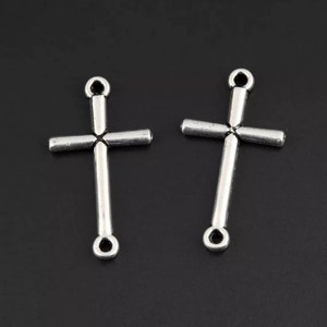 May include: Two silver-toned cross charms with a loop at the top for attaching to jewelry or other crafts.