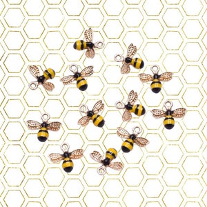 May include: A set of 12 gold bee charms with black and yellow enamel. The charms are arranged on a white background with a gold honeycomb pattern.