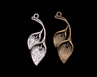 May include: Two silver and gold leaf charm pendants with a delicate floral design. The charms are shaped like two leaves with a stem.
