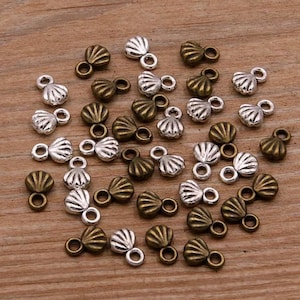 May include: A collection of 30 silver and bronze shell-shaped charms with a loop at the top. The charms are perfect for adding a touch of whimsy to jewelry making projects.