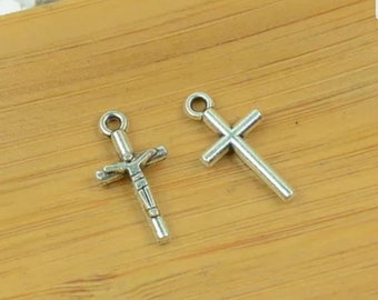 May include: Two silver cross charms, one with a simple design and the other with a more detailed design featuring a figure on the cross.