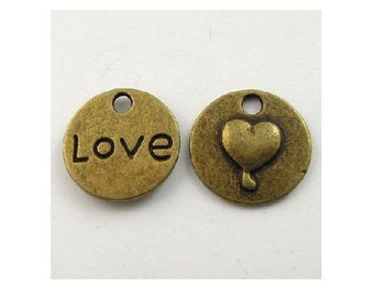 May include: Two antique gold-toned metal charms. One charm has the word "Love" engraved on it. The other charm has a raised heart shape.