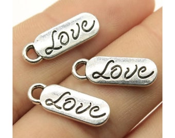 May include: Three silver charm pendants with the word "Love" written in a cursive font.