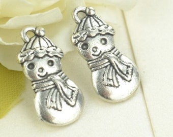 May include: Two silver charm pendants in the shape of a snowman. Each snowman has a round body, a hat, a scarf, and a smiling face.