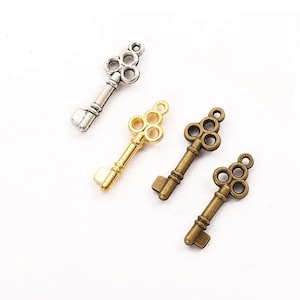May include: Four antique-style key charms in silver, gold, and bronze. Each key features a decorative, ornate design with four circles at the top.