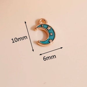 Op de afbeelding: Een goudkleurige maanvormige bedel met turquoise emaille en drie kleine sterren. De bedel is 10 mm hoog en 6 mm breed. Ideaal voor het maken van sieraden of knutselprojecten.