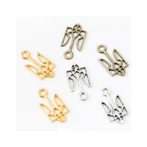 May include: Six metal charms in the shape of a trident with intricate details. Two charms are gold, two are silver, and two are bronze.