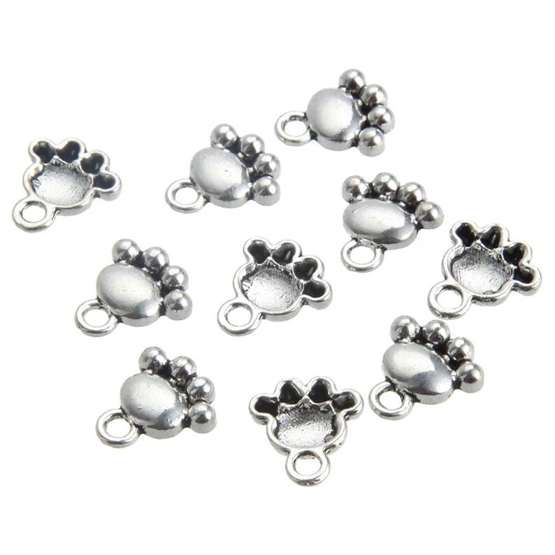 May include: Ten silver paw print charms with a loop for attaching to jewelry or other crafts.