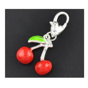 May include: Silver charm with a red and green enamel cherry design. The charm has a lobster claw clasp.