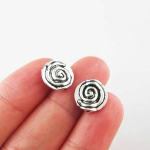 May include: Two silver-toned metal beads with a spiral design. The beads are round and have a textured surface.