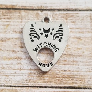 May include: Silver charm in the shape of a heart with the words "Witching Hour" and a crescent moon and stars design.