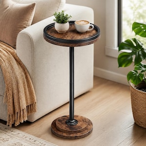 May include: A round side table featuring a dark wood-grain tabletop with a black metal rim, supported by a single black metal pole and a circular wood-grain base. A small white ceramic mug and a small green potted plant sit on the tabletop surface.