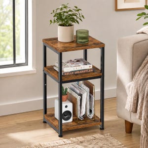 May include: A three-tier side table with a black metal frame and rustic brown wood-grain shelves. The top shelf holds a potted green plant and a green glass candle holder. The middle shelf holds books, and the bottom shelf holds a white speaker.