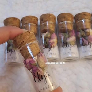 Peut inclure: Petits flacons en verre transparent avec bouchons en liège, contenant des boutons de rose séchés et une matière granuleuse blanche. Le verre porte l'inscription Elya en écriture cursive noire et la date 02.09.2023. Le texte @passiondeco.fr est visible.