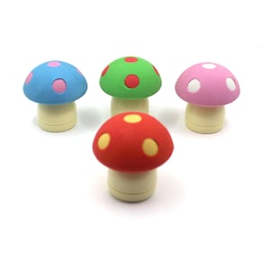 May include: Four mushroom-shaped erasers with cream-colored stems and rounded caps in blue, green, pink, and red. Each cap features contrasting circular spots: the blue cap has pink spots, the green has red, the pink has white, and the red has yellow.