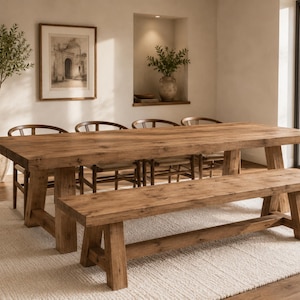 May include: A rectangular wooden dining table with a thick top and sturdy trestle legs, accompanied by a matching wooden bench positioned in front. The set features a natural wood grain finish with visible knots and a warm brown tone throughout.