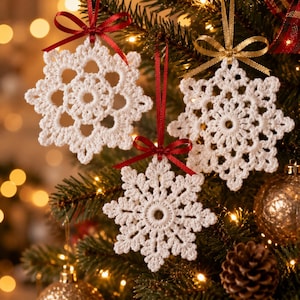 May include: Three white crocheted snowflake ornaments hanging from a Christmas tree. Each snowflake features intricate lace-like patterns and is suspended by a thin ribbon tied in a bow, with two red ribbons and one gold ribbon visible.