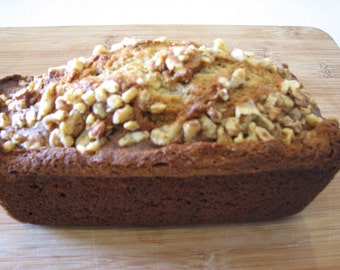 May include: A loaf of banana bread topped with chopped walnuts. The bread is golden brown and has a slightly crispy crust.