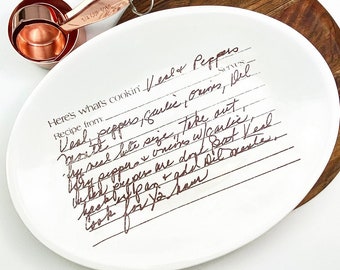 May include: White oval serving dish with a handwritten recipe for "Veal Peppers" in brown ink. The recipe includes ingredients like garlic, onions, and peppers. The dish is perfect for serving appetizers or snacks.