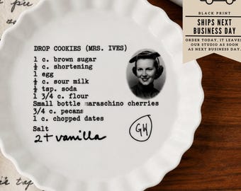 May include: A white ceramic fluted pie dish featuring a black printed recipe for Drop Cookies (Mrs. Ives). The text includes ingredients like brown sugar, shortening, egg, sour milk, soda, flour, maraschino cherries, pecans, dates, salt, and vanilla.