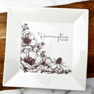 May include: White ceramic serving tray with a brown floral design and the text "The Harringtons est. 2022".