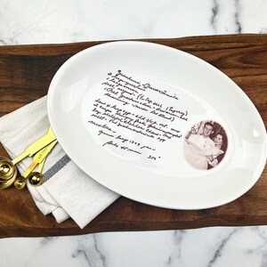 May include: White oval ceramic serving platter with a handwritten recipe for "Zucchini (Greastanie)" in black ink. The recipe includes ingredients like zucchini, eggs, flour, and sugar. The platter also features a black and white photo of a couple.