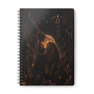 Puede incluir: Un cuaderno de espiral con una cubierta oscura de temática celestial que muestra a una persona junto a un león bajo una luna llena. El diseño incluye el símbolo del zodiaco Leo, el texto LEO y las palabras confident, generous, loyal, charismatic, strong, wise.