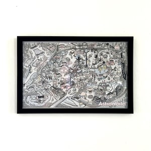 May include: Framed black and white illustration of AstroWorld amusement park, featuring detailed drawings of rides, attractions, and pathways. The text "AstroWorld 1997" is visible at the bottom right corner. The artwork is encased in a black frame.