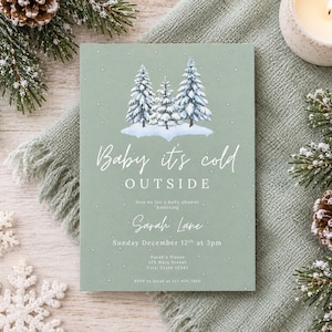 Op de afbeelding: Een saliegroene rechthoekige uitnodigingskaart voor een babyshower met een illustratie van besneeuwde dennenbomen en de tekst Baby it's cold OUTSIDE, Join us for a baby shower honoring Sarah Lane, Sunday December 12th at 3pm, Sarah's House.