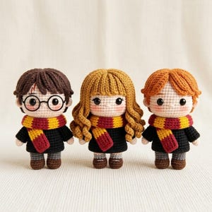May include: Three amigurumi dolls featuring dark brown, light brown, and ginger yarn hair. Each doll wears a black sweater, brown shoes, and a yellow and maroon striped scarf. The doll on the left has round black glasses and a red lightning bolt mark.
