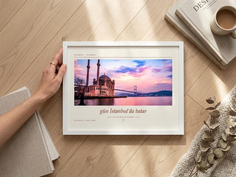 May include: A white framed wall art print featuring a photograph of the Ortak&ouml;y Mosque in Istanbul at sunset with a pink and blue sky. The print includes the text Ortak&ouml;y - Istanbul, g&uuml;n İstanbul'da batar, and the sun sets in Istanbul.