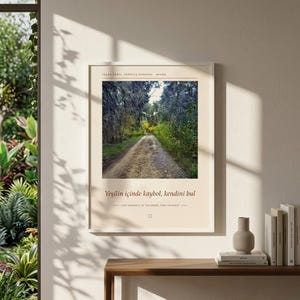 Puede incluir: Una l&aacute;mina de arte mural rectangular con una fotograf&iacute;a de un camino de tierra que serpentea a trav&eacute;s de un bosque denso. El texto dice YAŞAR KEMAL Y&Uuml;R&Uuml;Y&Uuml;Ş PARKURU ADANA, Yeşilin i&ccedil;inde kaybol, kendini bul y LOSE YOURSELF IN THE GREEN, FIND YOURSELF.